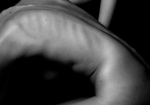 a naked woman sitting on a table with her back to the camera