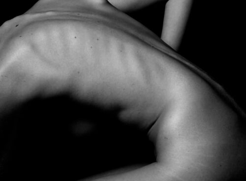 a naked woman sitting on a table with her back to the camera