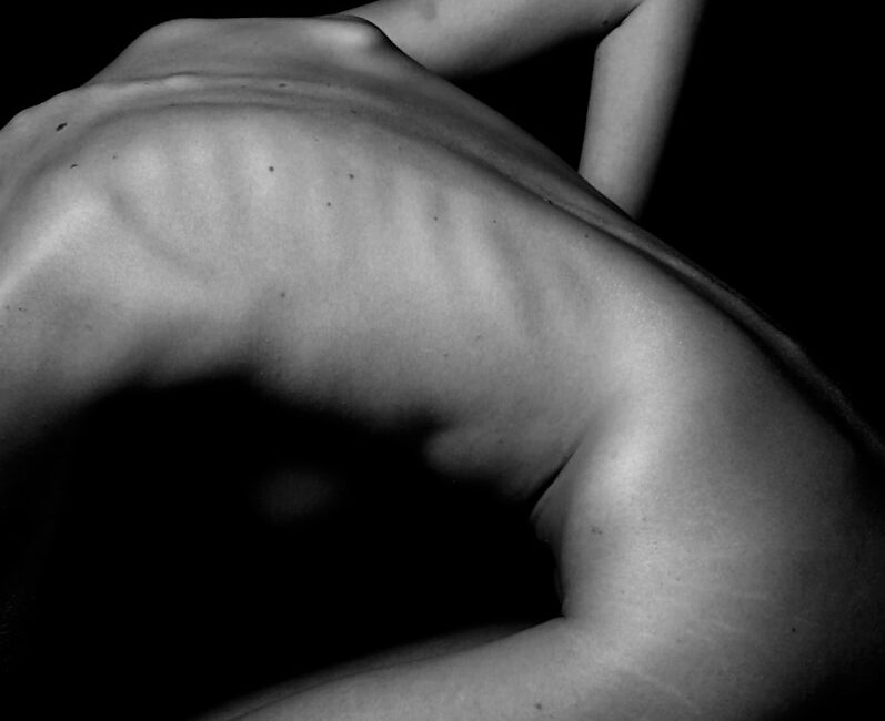 a naked woman sitting on a table with her back to the camera