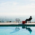 a person sitting in a chair by a pool