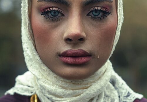 A woman is wearing a headscarf, looking sad.