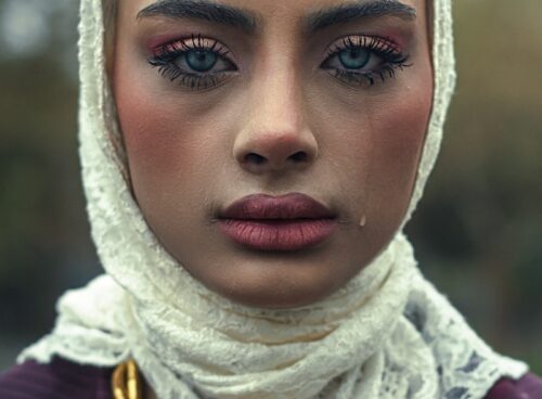 A woman is wearing a headscarf, looking sad.