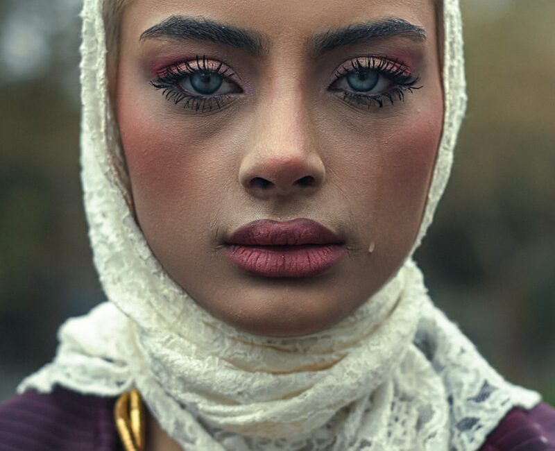 A woman is wearing a headscarf, looking sad.