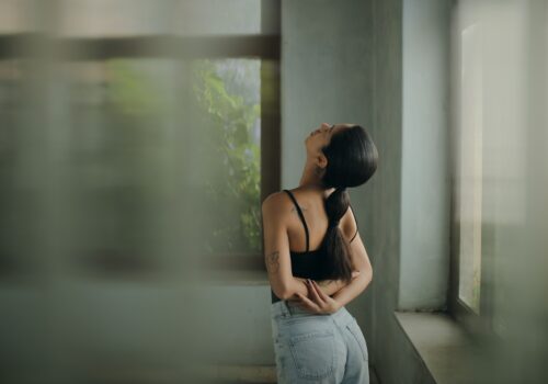 A woman leaning against a wall with her head in her hands