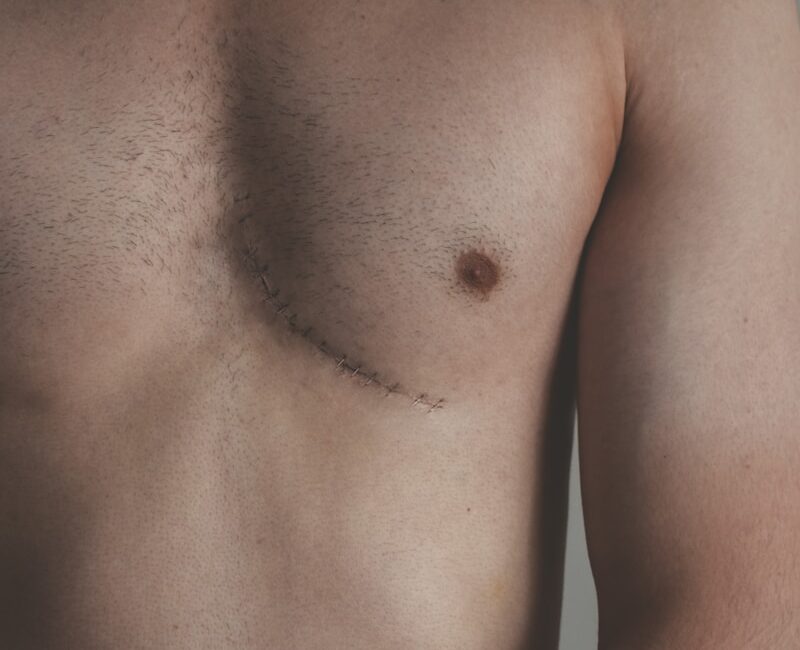 topless man standing near white wall