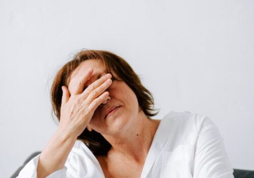 a woman sitting on a couch holding her hands to her face