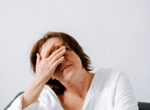 a woman sitting on a couch holding her hands to her face