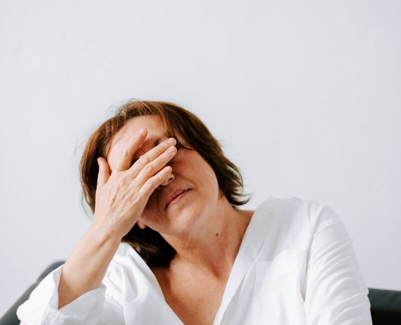 a woman sitting on a couch holding her hands to her face