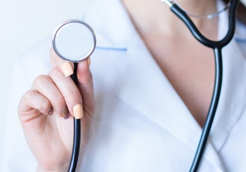 a woman in a white shirt holding a stethoscope